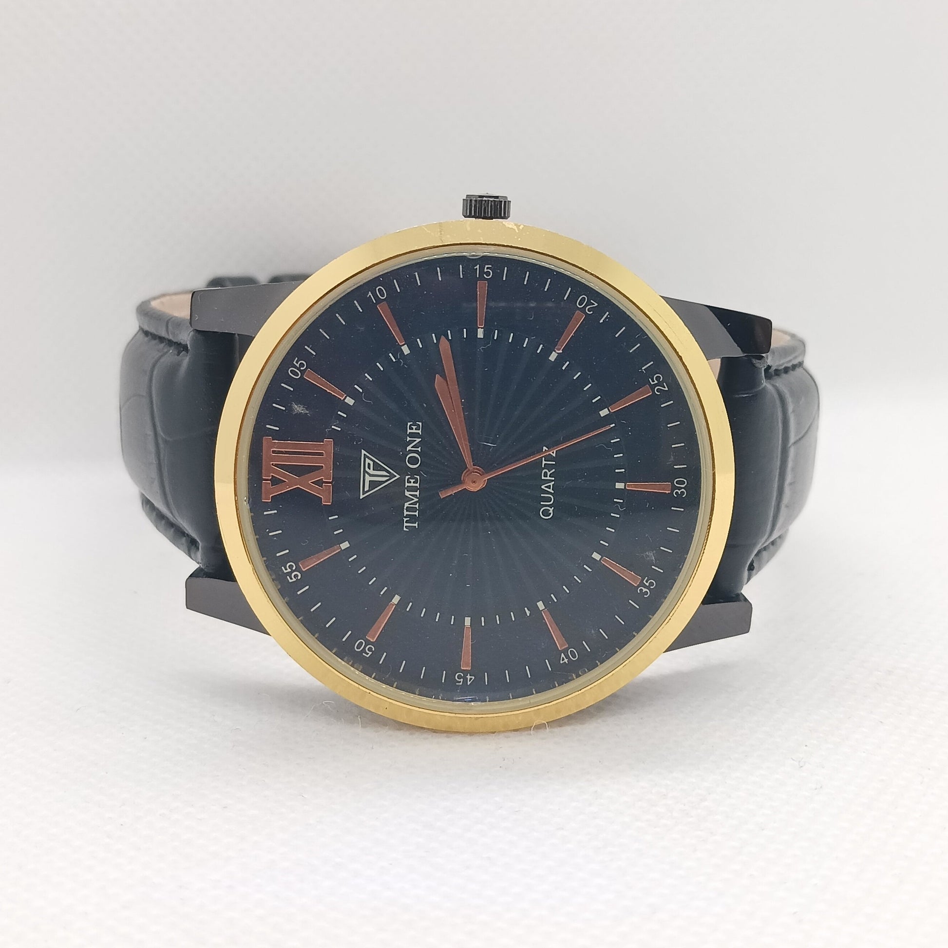 Watch with black strap and gold bezel on a white background