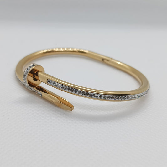 Gold bracelet with small stones on a light gray background