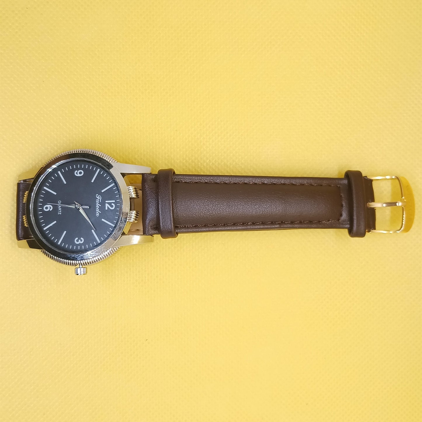 Watch with brown leather strap on a yellow background