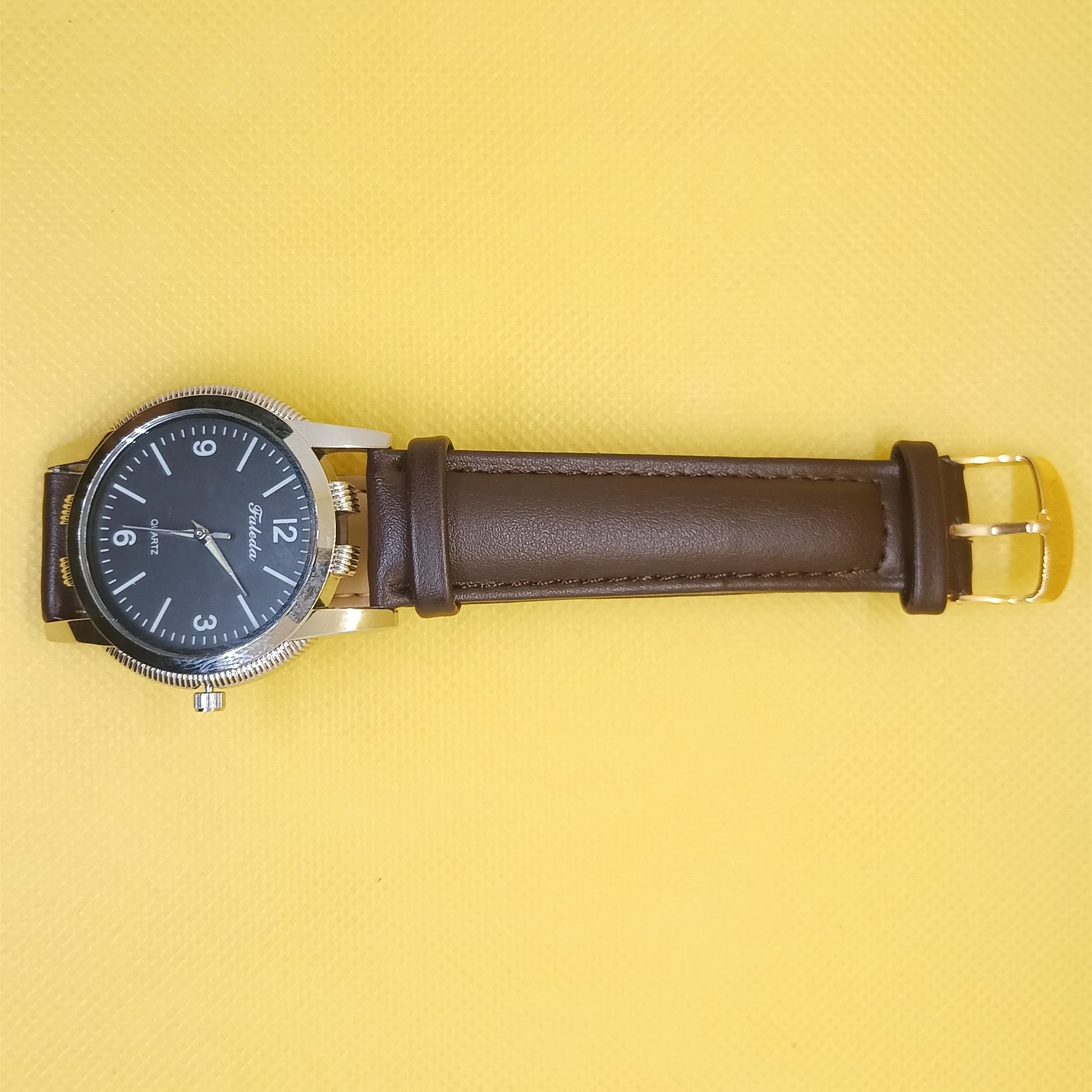 Watch with brown leather strap on a yellow background