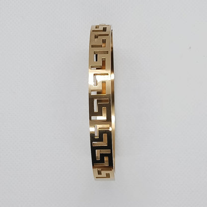 Gold bracelet with a geometric pattern on a light gray background