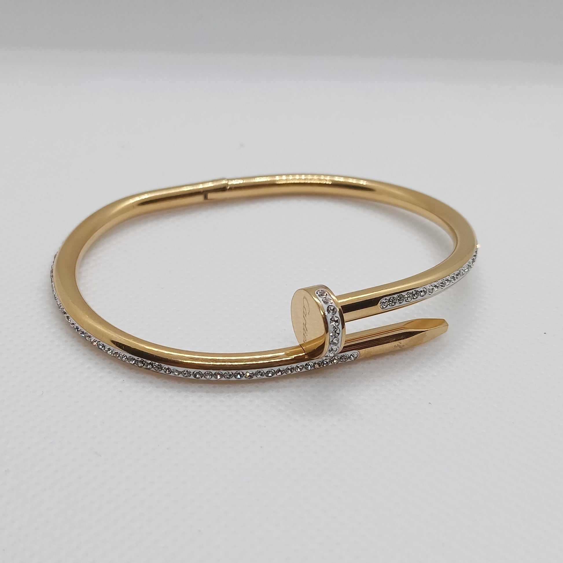 Gold bracelet with a diamond on a light gray background