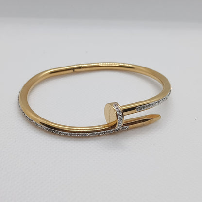 Gold bracelet with a diamond on a light gray background