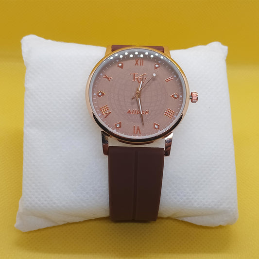 Watch with brown strap and pinkish dial on a white cushion against a yellow background