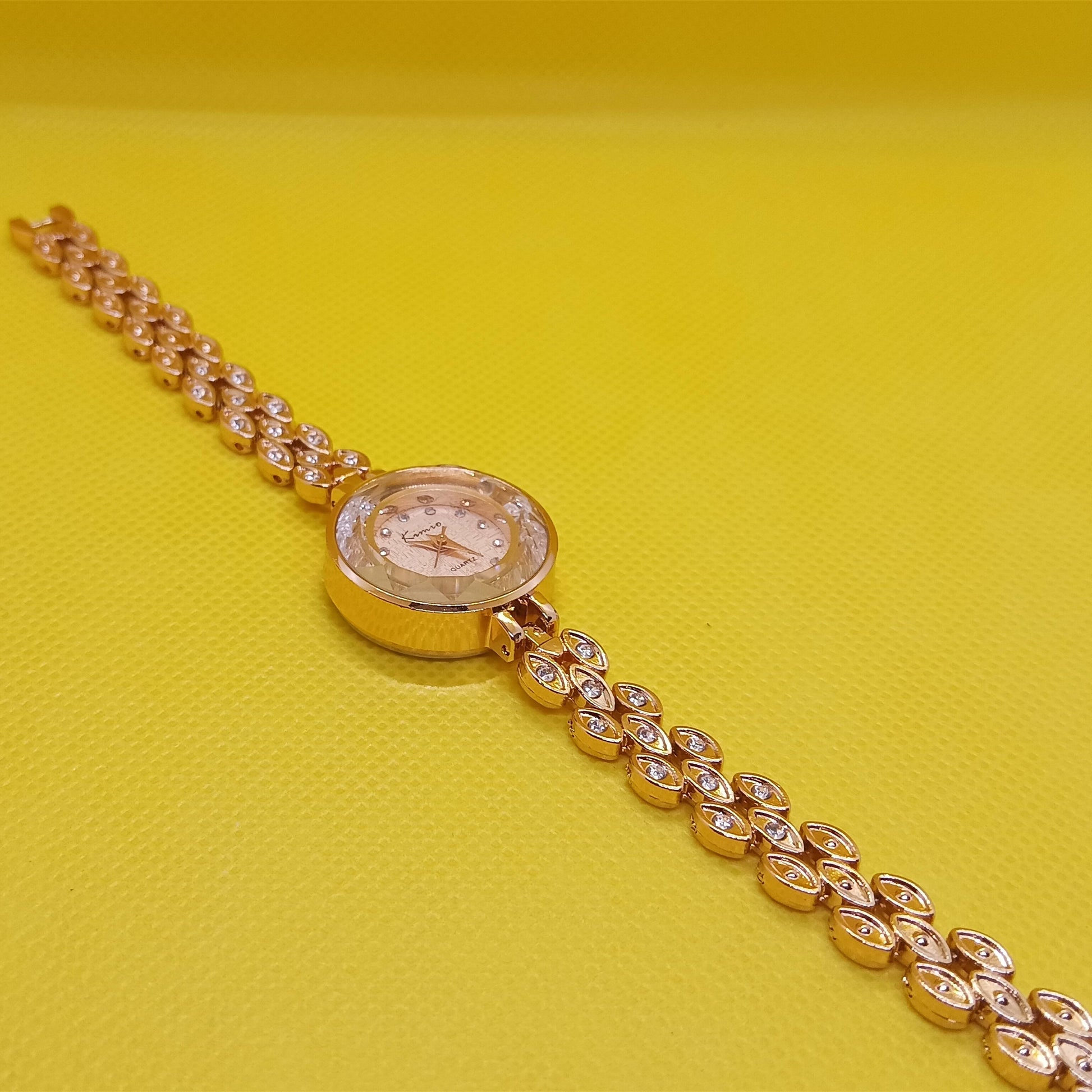Gold wristwatch with diamond-studded chain on a yellow background
