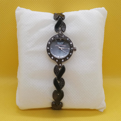 Black braided watch on a white cushion against a yellow background