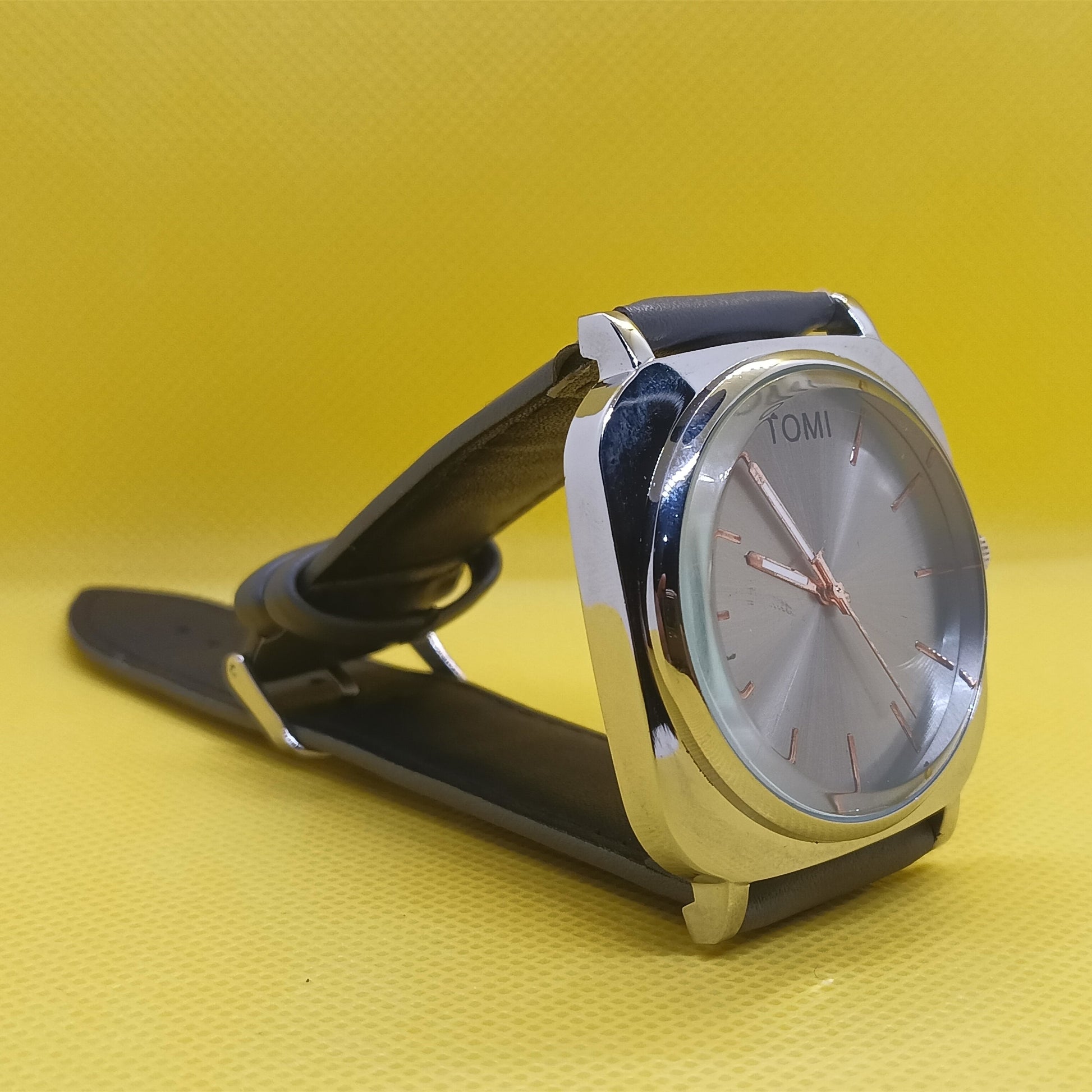 Wristwatch with black strap and silver case on a yellow background