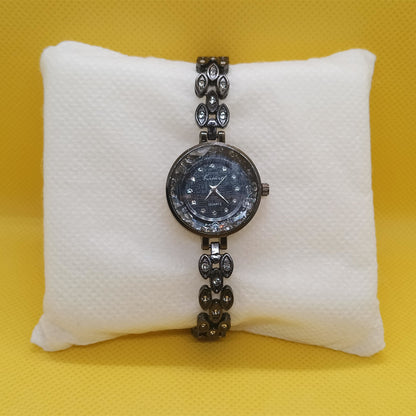 Wristwatch with decorative band on a white cushion against a yellow background