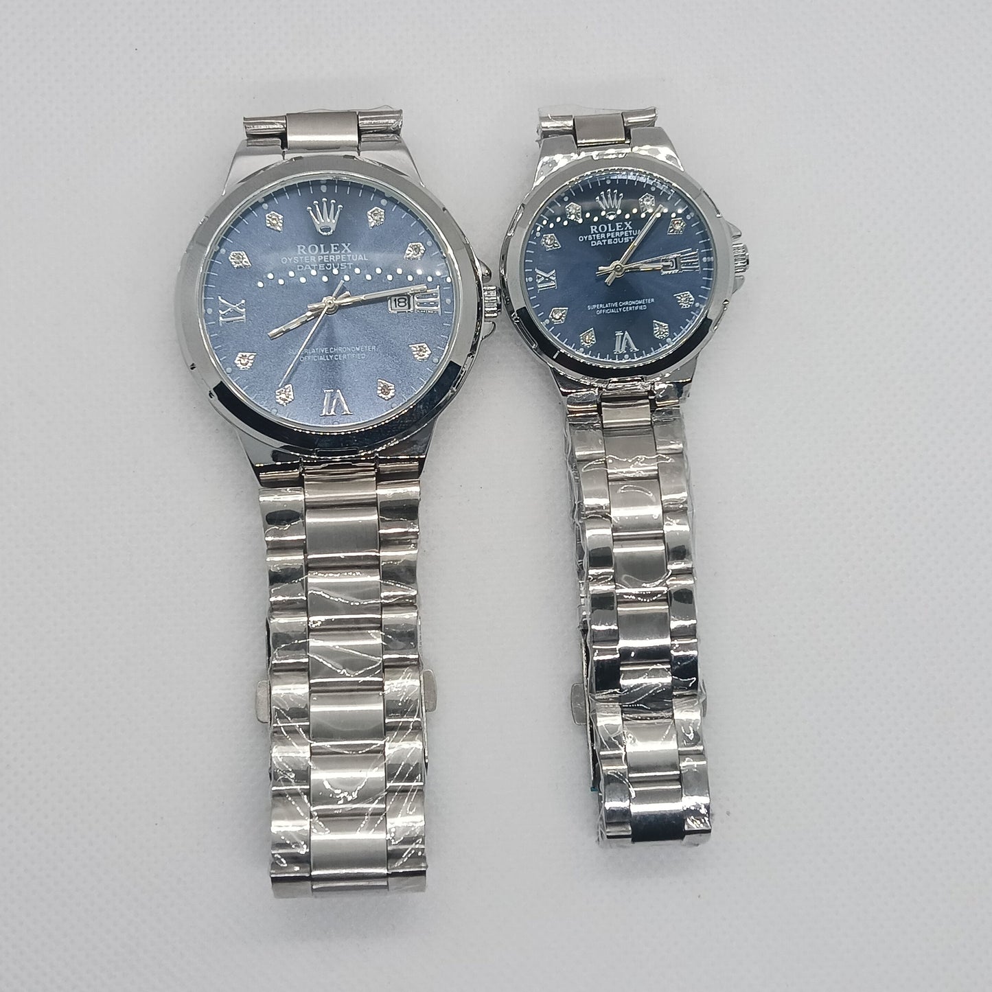 Two silver wristwatches with blue faces on a light gray background