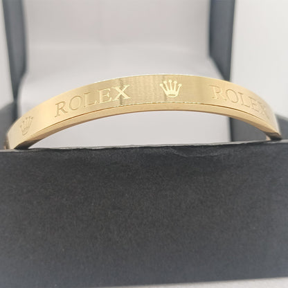 Gold bracelet with Rolex engraving on a gray background