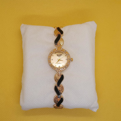 Decorative watch with gold and black design on a white cushion against a yellow background