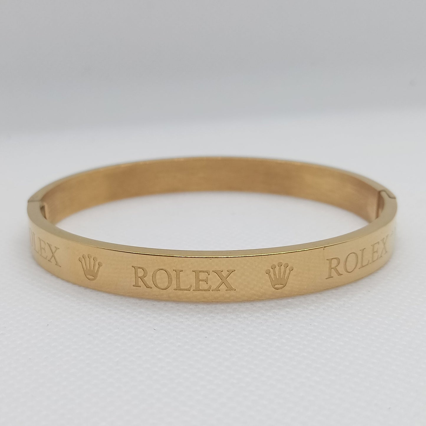 Gold bracelet with 'Rolex' engraving on a white background