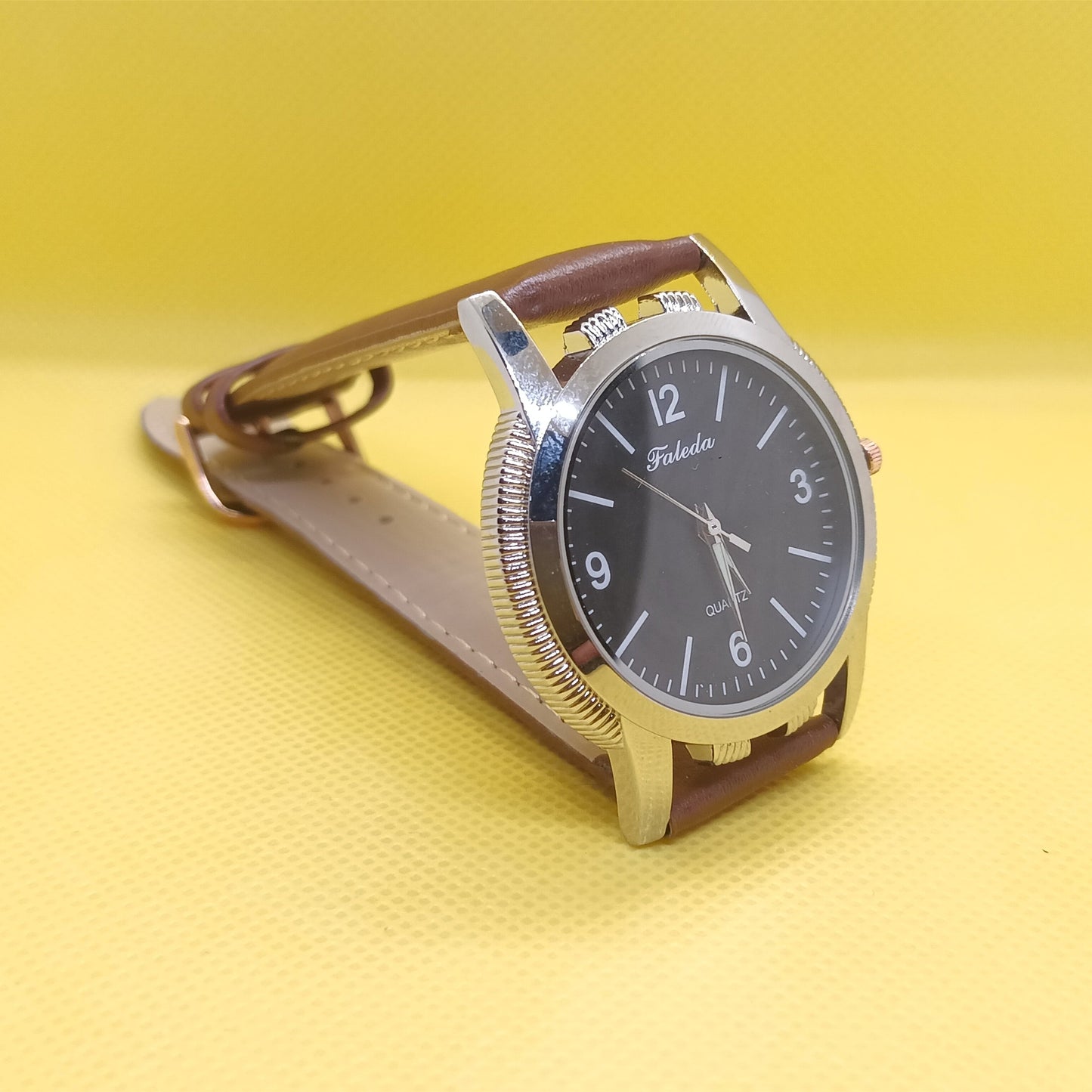 Wristwatch with brown strap and black dial on a yellow background