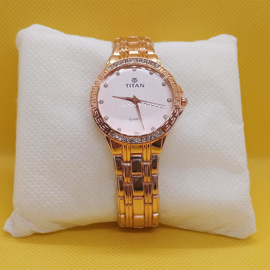 Gold Titan watch on a white cushion with a yellow background