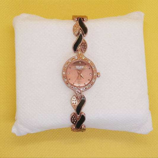 Rose gold watch with decorative band on a white cushion against a yellow background