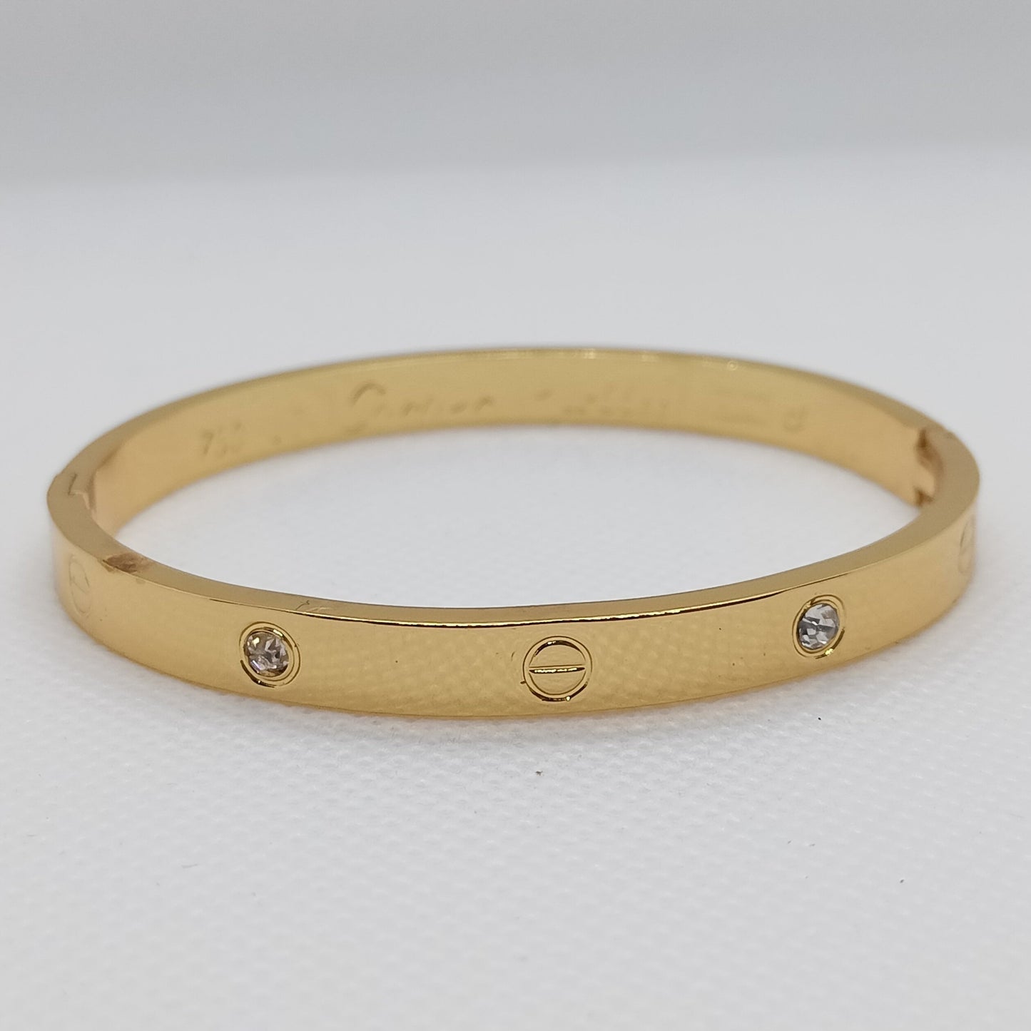 Gold bracelet with embedded stones on a light gray background