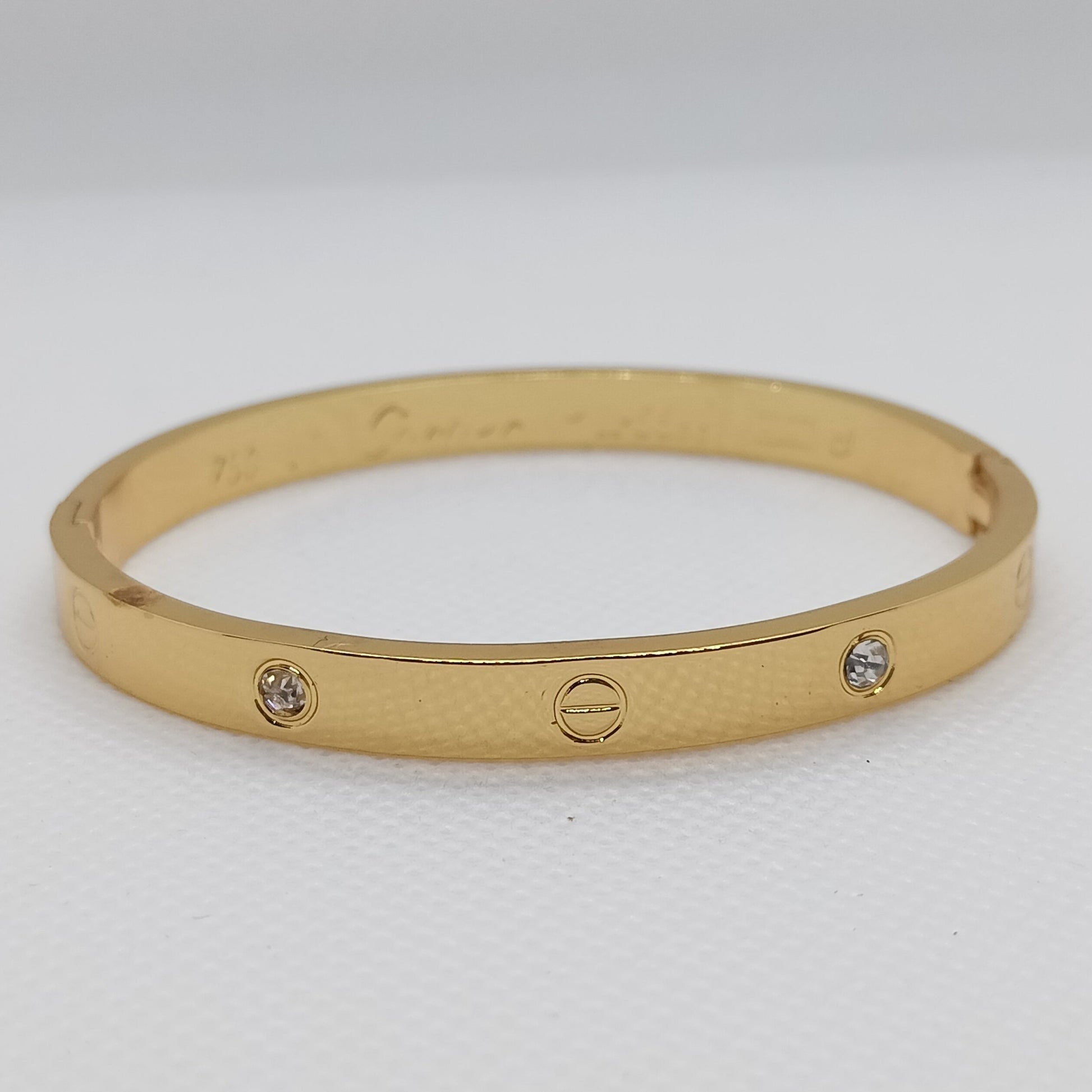 Gold bracelet with embedded stones on a light gray background