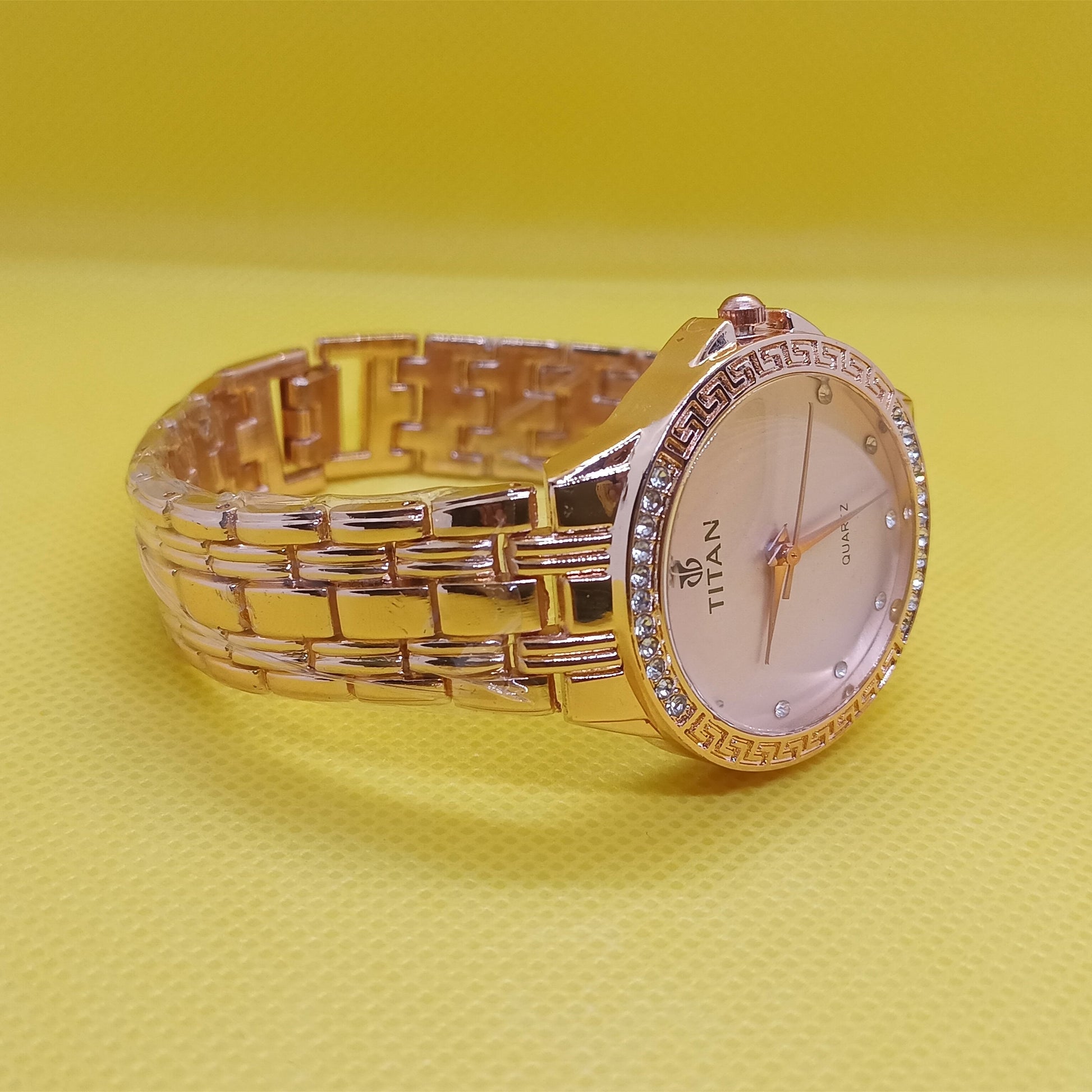 Gold wristwatch with a visible brand name on a yellow background